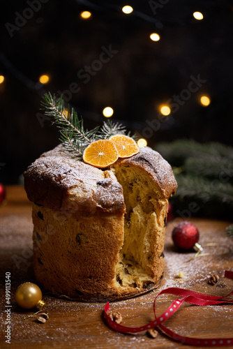 Rustic homemade Christmas traditional Italian holiday panettone cake with festive ribbon, decoration and lights