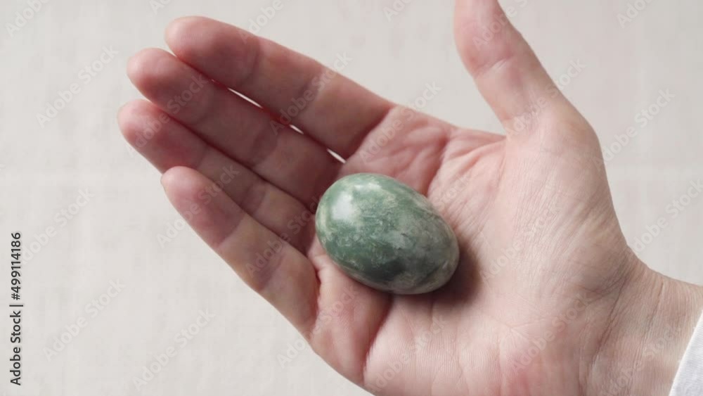 Female hand holding a green jade egg Female hand holding a green jade egg