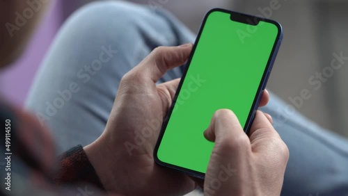 Man Using Smartphone in Vertical Mode with Green Mock-up Screen, Doing Swiping, Scrolling Gestures. Internet Social Networks Browsing News, Financial Reports