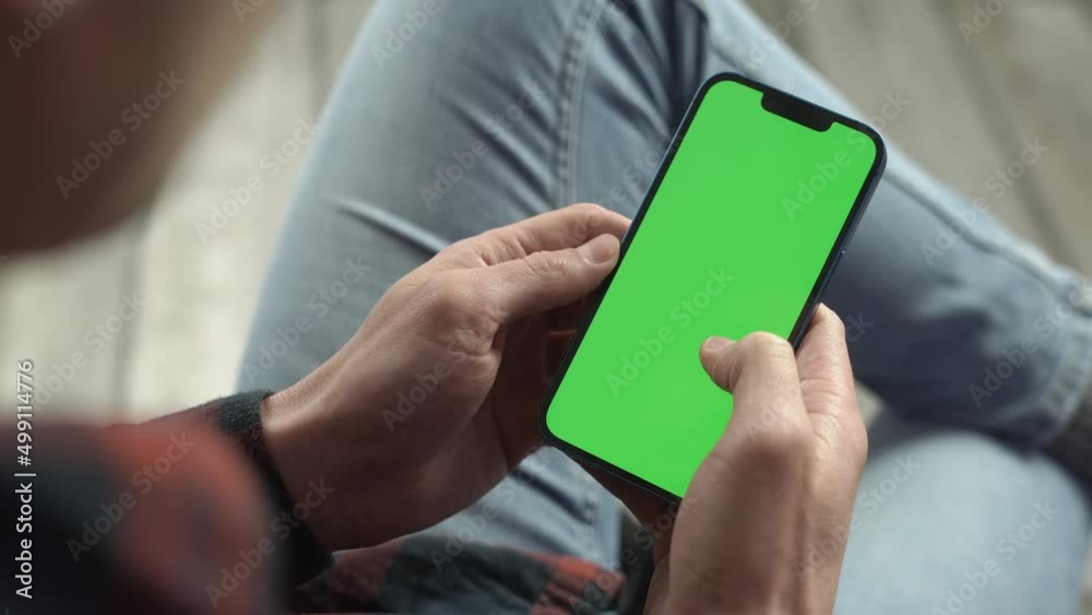 Man Using Smartphone in Vertical Mode with Green Mock-up Screen, Doing Swiping, Scrolling Gestures. Internet Social Networks Browsing News, Financial Reports