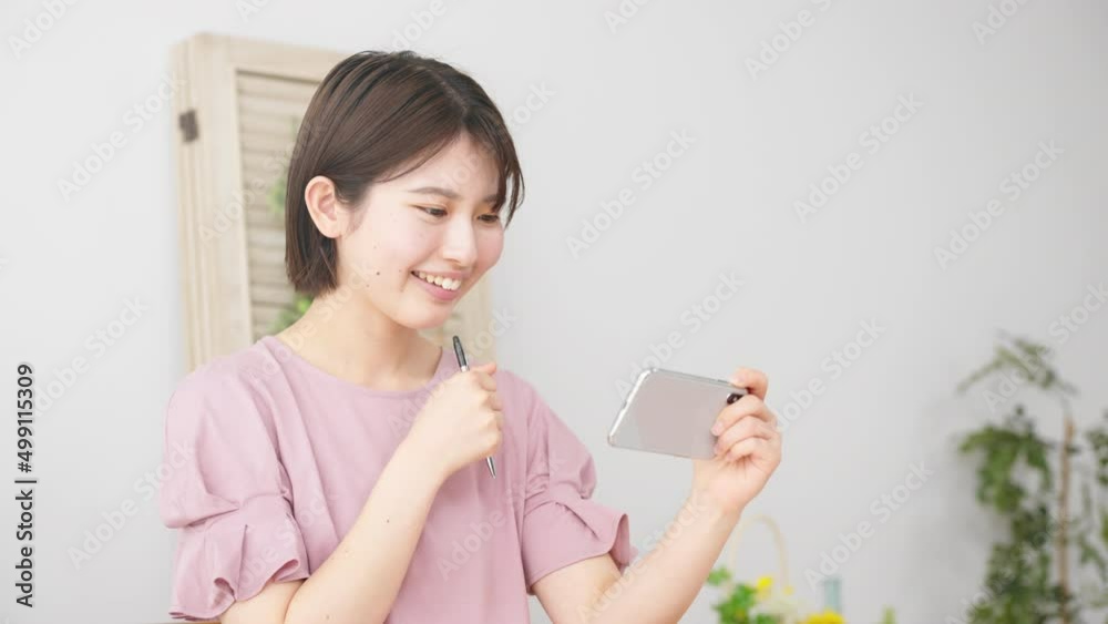 スマートフォンを観ながら勉強をする女性 スマートフォンを観ながら勉強をする女性