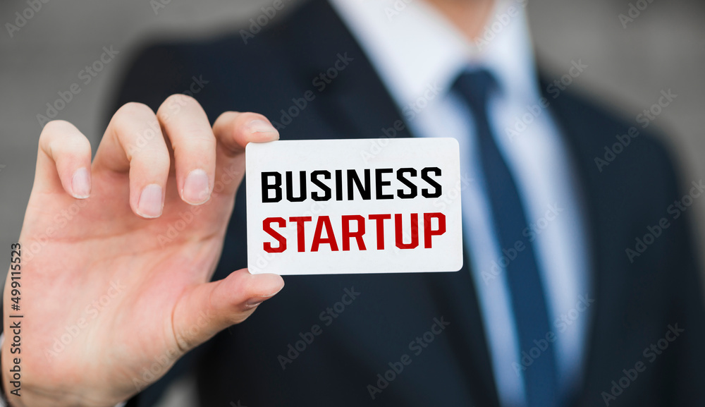 Business concept. Businessman shows a card with the text - BUSINESS STARTUP Business concept. Businessman shows a card with the text - BUSINESS STARTUP