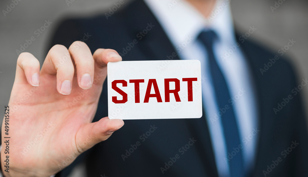 Start. Man student holds notebook with word start, beginning of classes at school, in college. Brick building and talking students background Start. Man student holds notebook with word start, beginning of classes at school, in college. Brick building and talking students background
