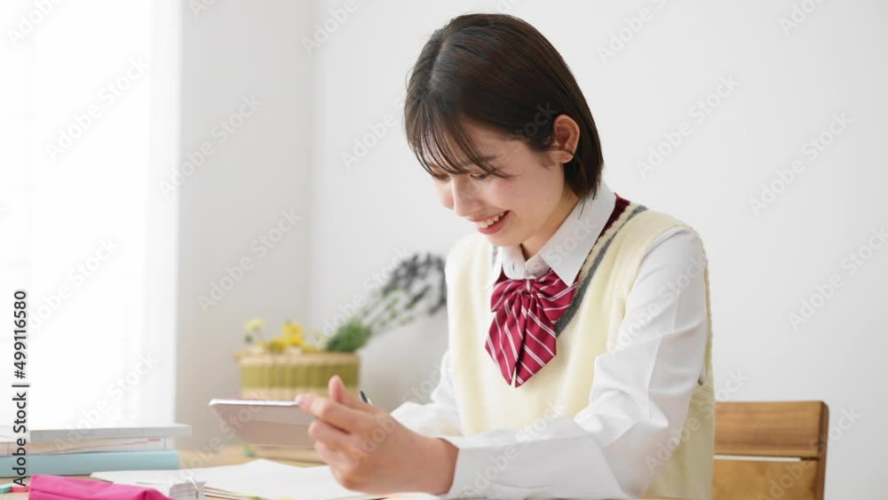 スマートフォンを観ながら勉強をする女子高生 スマートフォンを観ながら勉強をする女子高生