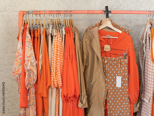 Ropa tonos naranja en perchero de tienda de ropa photo