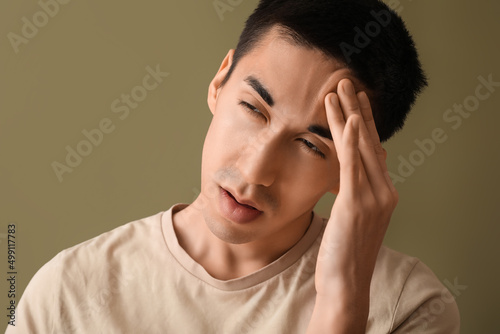 Young Asian man worrying on color background, closeup