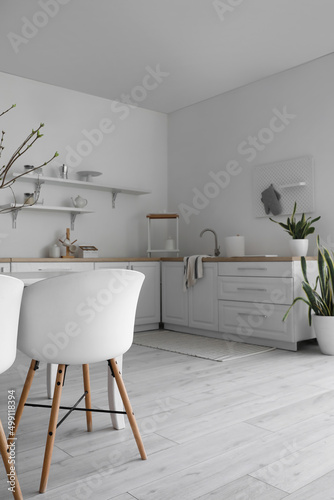 Chairs  modern counters and shelves with kitchenware near white wall in room interior