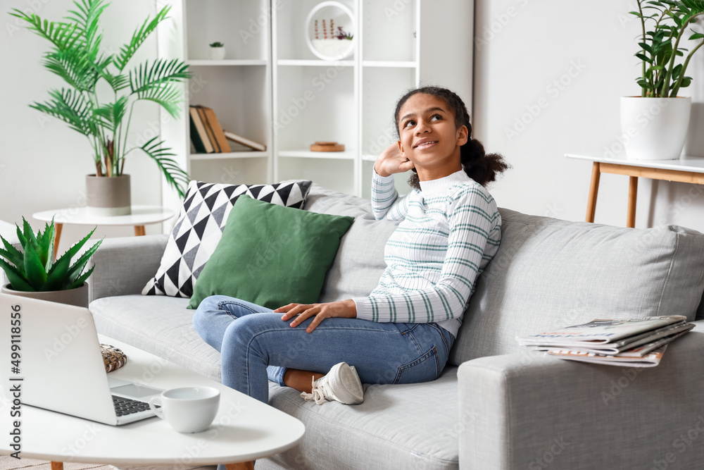 African-American teenage girl relaxing on sofa at home African-American teenage girl relaxing on sofa at home