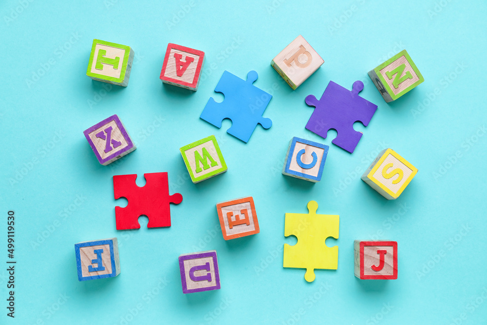 Wooden cubes with letters and puzzle pieces on blue background
