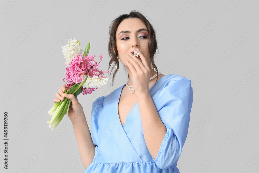 Pretty young woman with hyacinth flowers on grey background Pretty young woman with hyacinth flowers on grey background