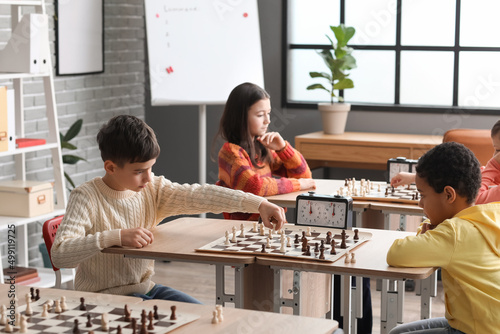 Little children playing chess during tournament in club