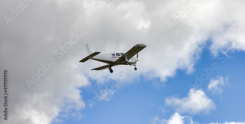 Single Engine Small Airplane taking off from an Airport. Cloudy Sky in Background.