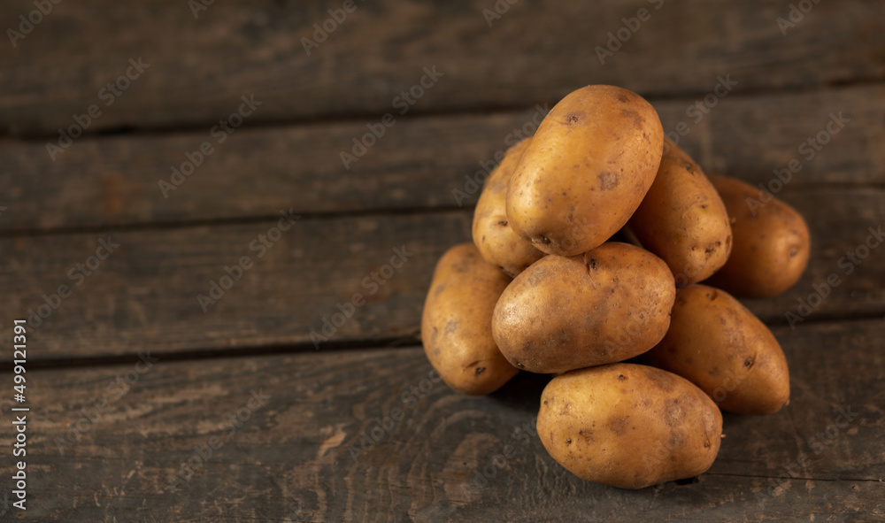 A pile of potatoes on the background of a wooden box. Concept: a bunch of potatoes, vegetable garden, farming, agriculture A pile of potatoes on the background of a wooden box. Concept: a bunch of potatoes, vegetable garden, farming, agriculture