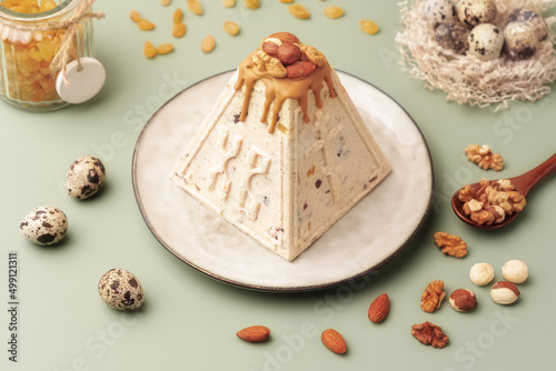 Foto Traditional Easter cottage cheese dessert Paskha decorated with caramel, nuts, raisins and quail eggs on pastel background