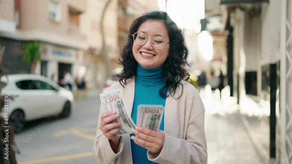Young chinese woman smiling confident counting dollars at street Young chinese woman smiling confident counting dollars at street