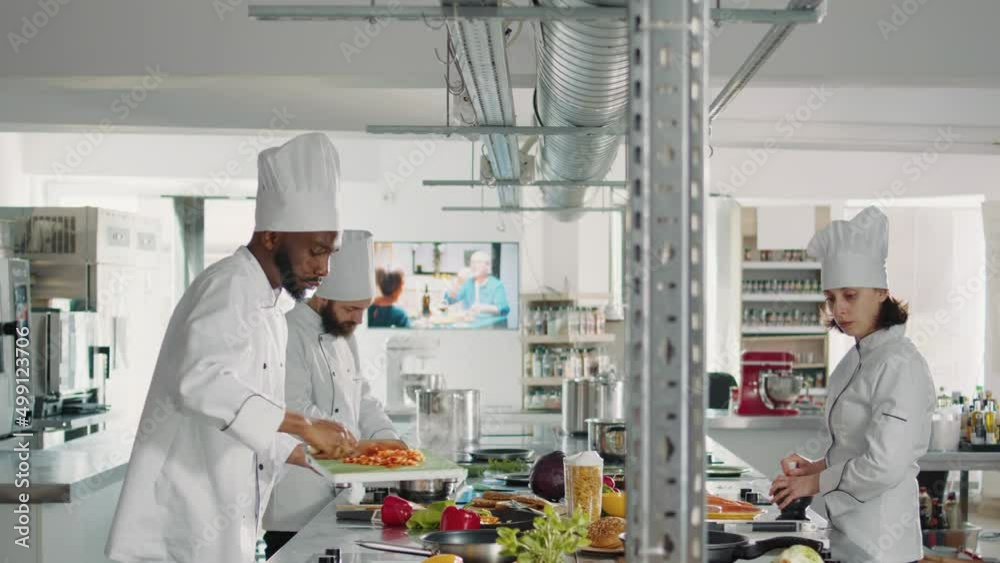 African american cook cutting bell pepper and adding in pan, cooking vegetable cuisine recipe. Chef in uniform chopping ingredients on cutting board and making professional gourmet dish.