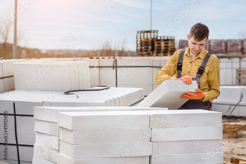  man contractor builder is holding an autoclaved aerated concrete block aac on a construction site.