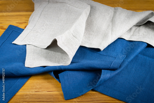Linen napkins in blue and natural color folded on wooden background