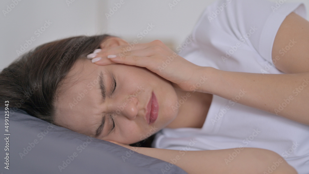 Woman having Headache while Sleeping in Bed Woman having Headache while Sleeping in Bed