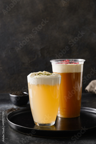 Fototapeta Naklejka Na Ścianę i Meble -  Cheese tea in glasses made of green tea and black tea with whipped cream cheese foam on black background. Vertical format.