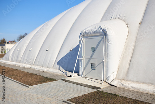 Inflatable air dome stadium. Inflated Tennis air dome or Tennis bubble arena entrance door into structure equipped with airlock either two sets of parallel doors or a revolving door or both. photo