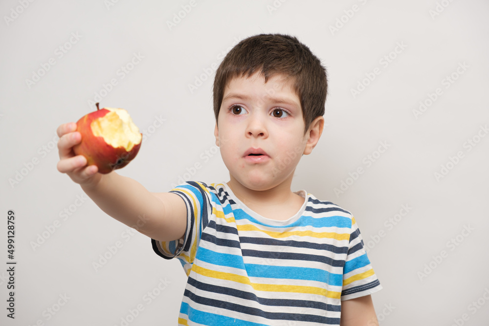 A 4 year old boy eats a red apple and squirms. The child does not like fruit A 4 year old boy eats a red apple and squirms. The child does not like fruit