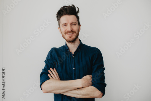 Handsome young man in a dark blue shirt by a light wall. Place for text.