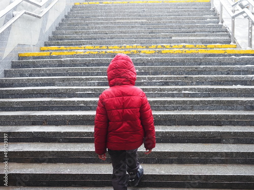 Fotografia a child a boy in a red jacket comes out of the underpass on the steps during a s