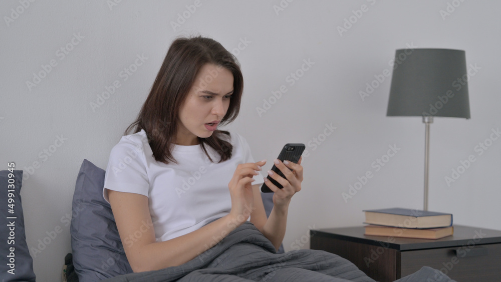 Woman Reacting to Loss on Smartphone in Bed Woman Reacting to Loss on Smartphone in Bed