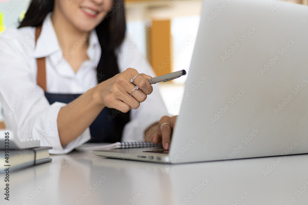 Small start-up business owners work with laptops in warehouses. A woman checks online orders in preparation for delivery. E-commerce business concept. Small start-up business owners work with laptops in warehouses. A woman checks online orders in preparation for delivery. E-commerce business concept.