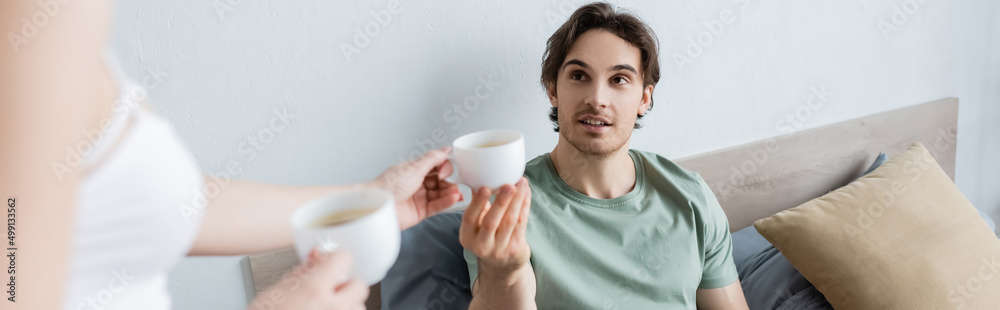 blurred woman giving cup of coffee to boyfriend in bed, banner. blurred woman giving cup of coffee to boyfriend in bed, banner.