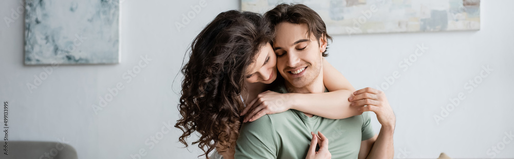 curly woman hugging happy boyfriend with closed eyes, banner.