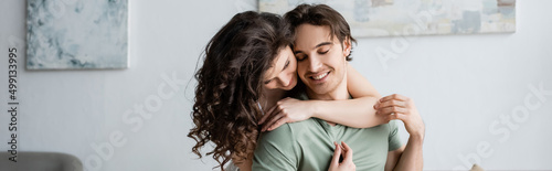 curly woman hugging happy boyfriend with closed eyes, banner.