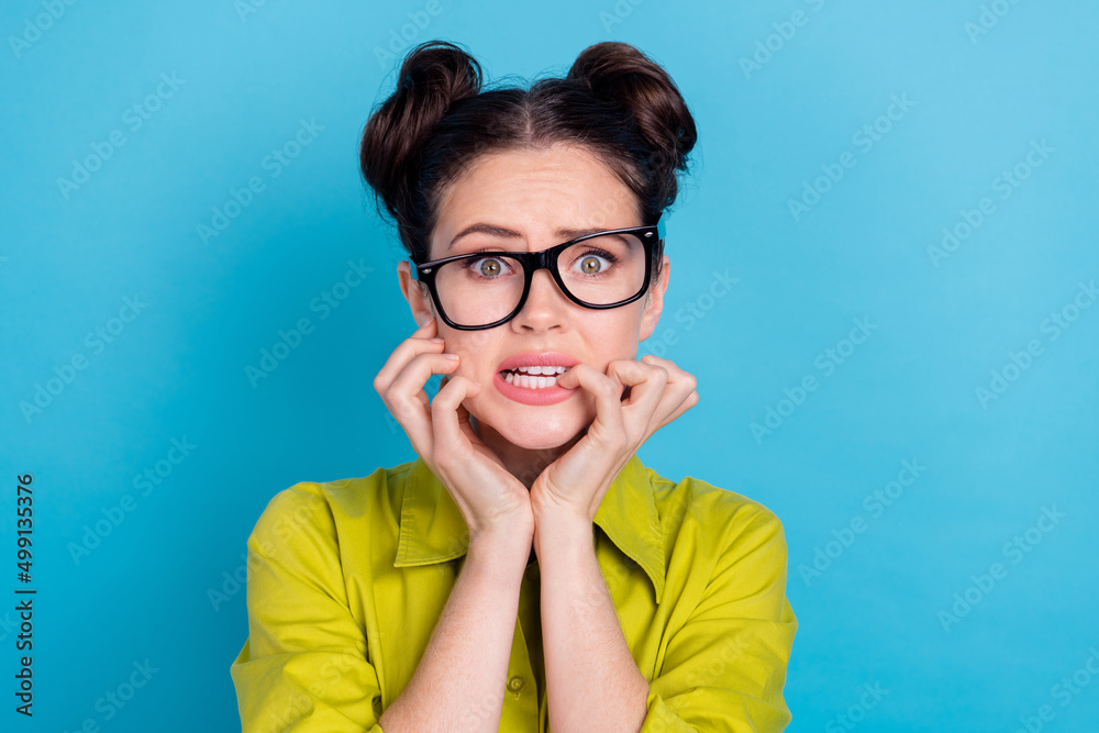Portrait of unsatisfied anxious girl bite finger nails stare camera isolated on blue color background Portrait of unsatisfied anxious girl bite finger nails stare camera isolated on blue color background