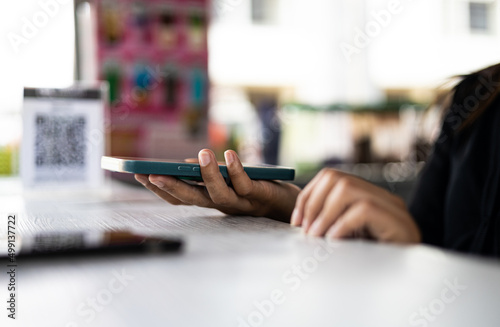 Close-up view of young woman holding mobile phone in hand on a white table.
