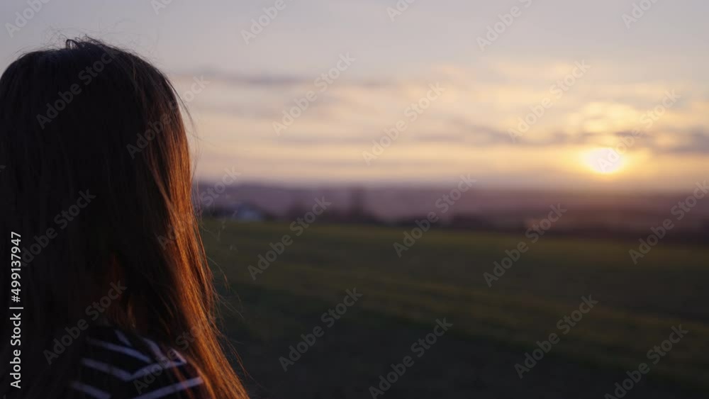 Young woman enjoying mountain sunset. Rear view Young woman enjoying mountain sunset. Rear view