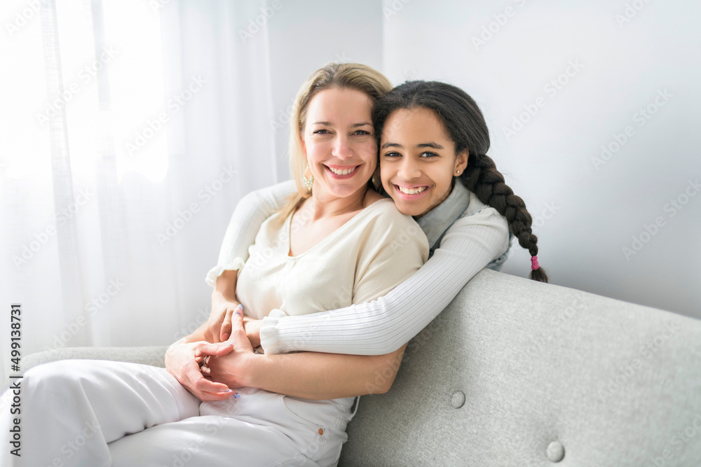 Adorable black teen daughter with mother sit on sofa at home Adorable black teen daughter with mother sit on sofa at home