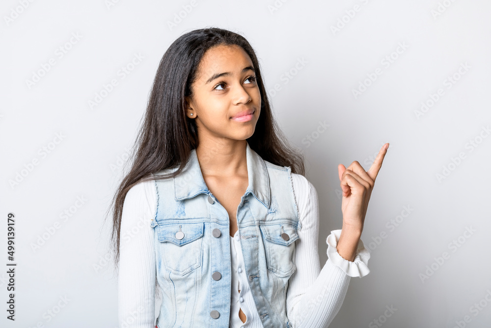 Beautiful black teen posing on studio white background pointing something Beautiful black teen posing on studio white background pointing something