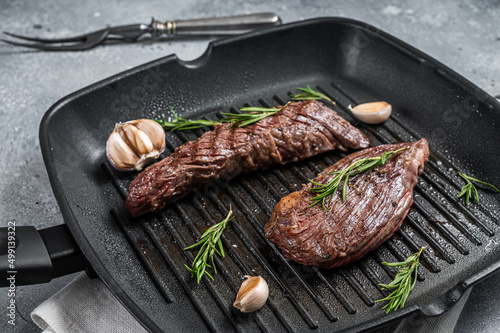 Roasted on a grill skillet Flank flap or Bavette beef meat steak with rosemary. Gray background. Top view