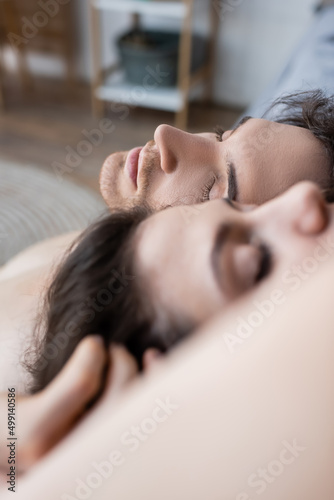 close up view of young man with closed eyes lying near blurred girlfriend.