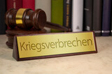Gavel and law book with sign and the german word for war crimes - Kriegsverbrechen on a wooden table