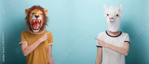 Fényképezés Woman in lion and alpaca mask pointing with index finger to the blank space, or
