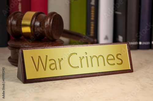 Gavel and law book with sign and war crimes on a wooden table photo