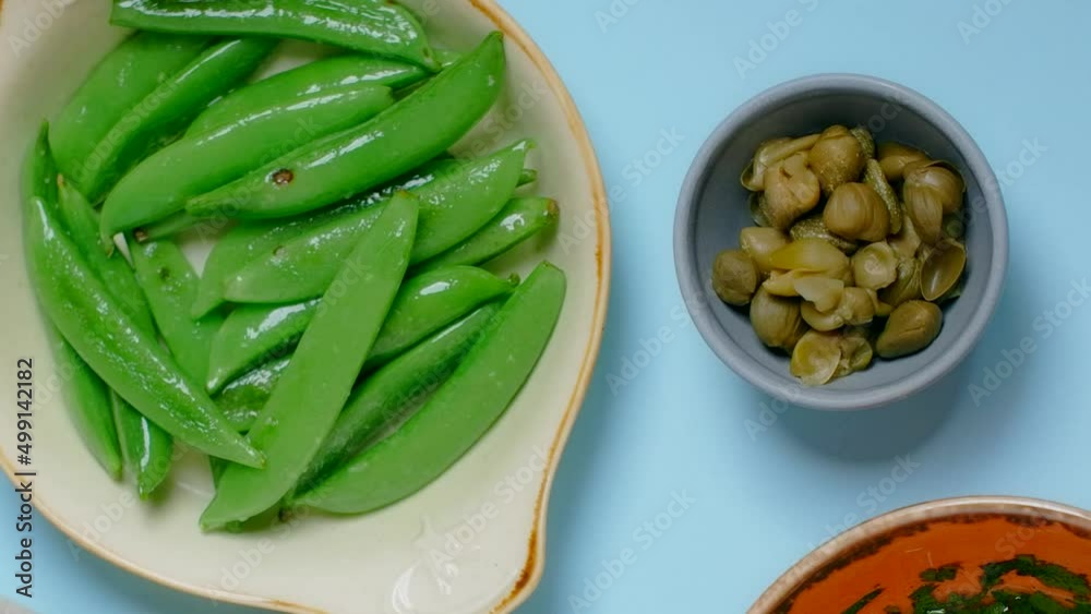 Vertical tabletop video: chef puts plate with coocked sweet pea pods to the table Vertical tabletop video: chef puts plate with coocked sweet pea pods to the table