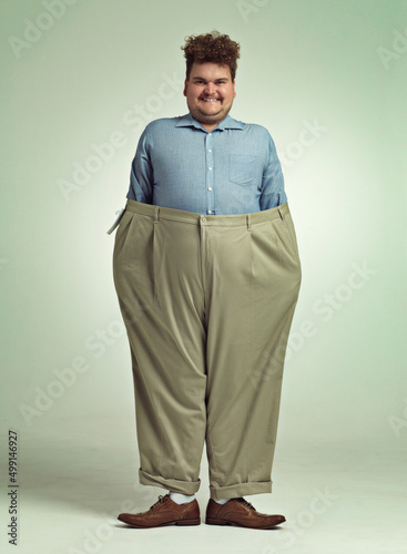 Diet progress. Shot of an overweight man wearing a pair of oversized pants looking pleased. photo