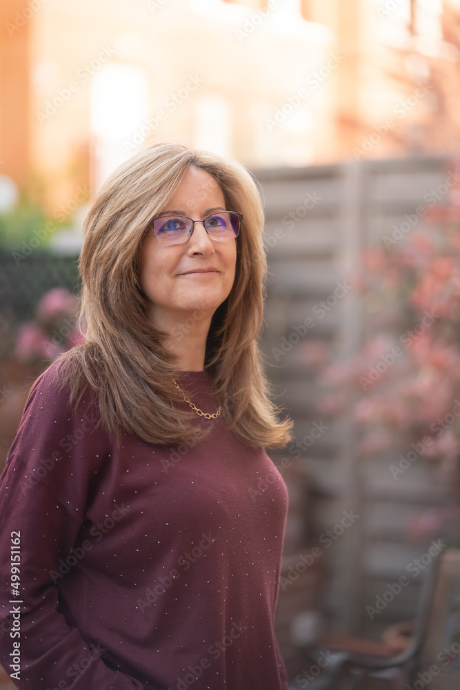 Mature white woman smiling in a happy attitude in the garden of her house.