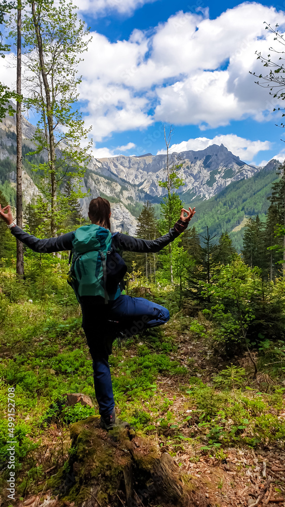Mindful woman performing yoga and meditating in a vibrant forest with a scenic view on Karlhochkogel in the Hochschwab Region in Upper Styria, Austria. Breathing and relaxing in the Alps, Europe