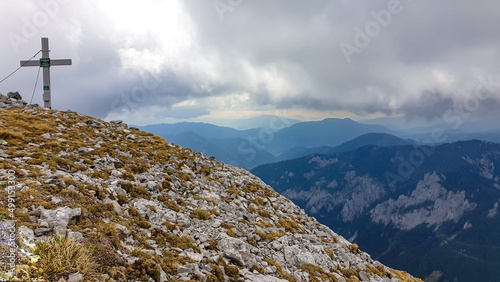 Scenic view from the summit cross of mount Zinken in the Hochschwab Region, Upper Styria, Austria. Valley is covered with clouds. Weather change on rainy spring day in the Alps, Europe. Alpine terrain