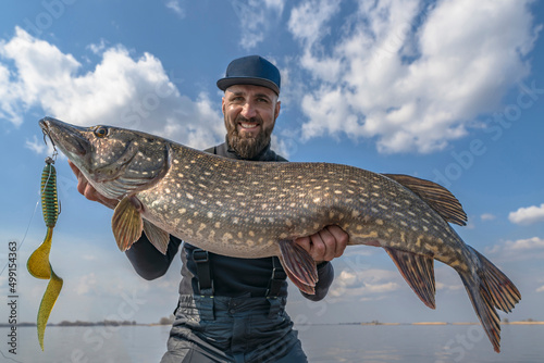 Success pike fishing. Happy fisherman with big fish trophy at boat photo