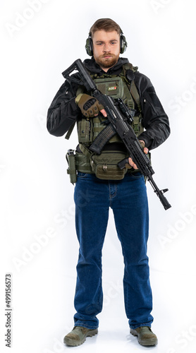 soldier, airsoft player in full gear with a machine gun. a man in headphones, a bulletproof vest, with a backpack and a full-length belt. White background.